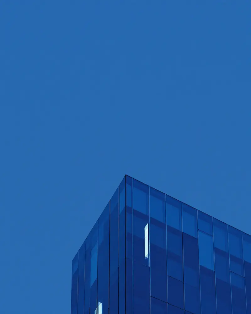 Blue glass skyscraper corner against a clear blue sky